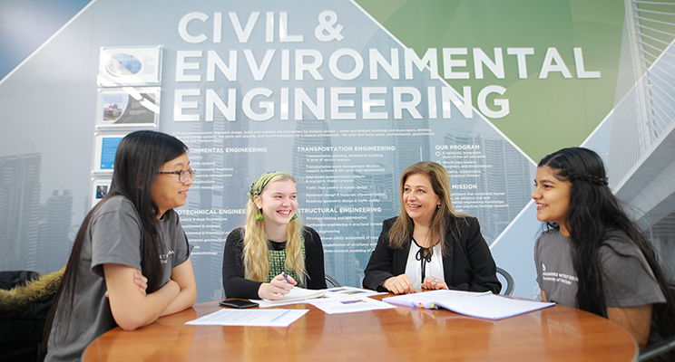 Three female UToledo engineering students sitting at a table with a faculty member